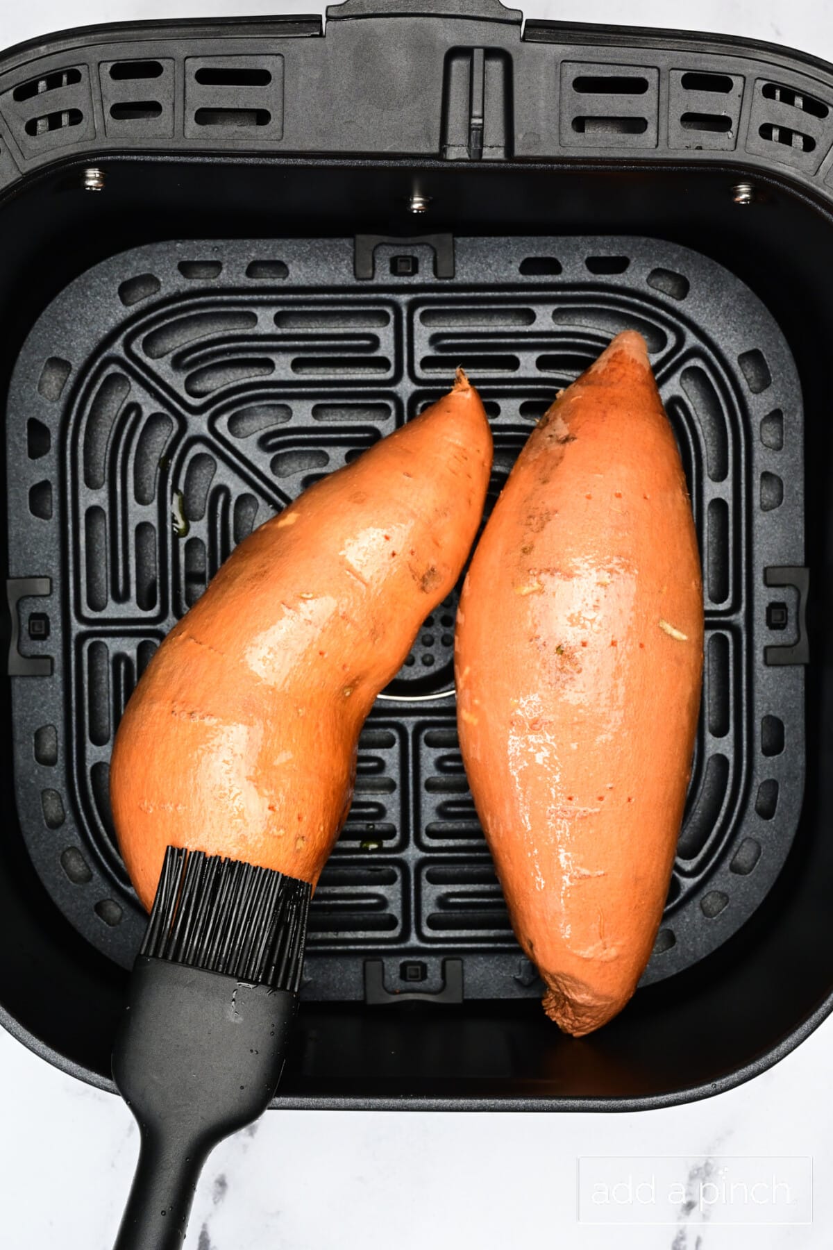Prepping two sweet potatoes in air fryer.
