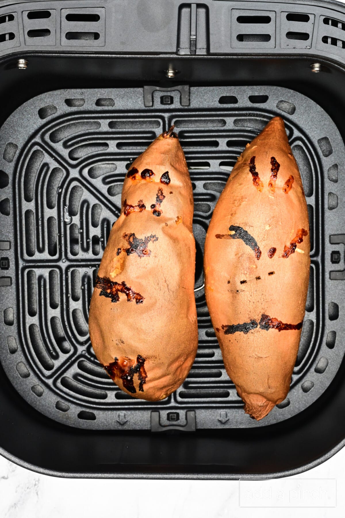 Two air fryer sweet potatoes in the air fryer basket.