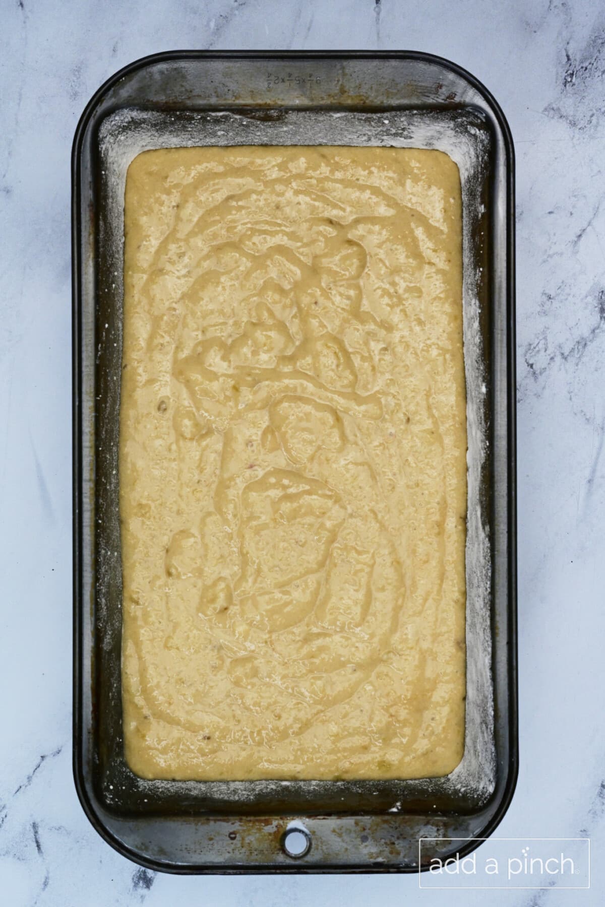 Banana bread batter added to prepared loaf pan.