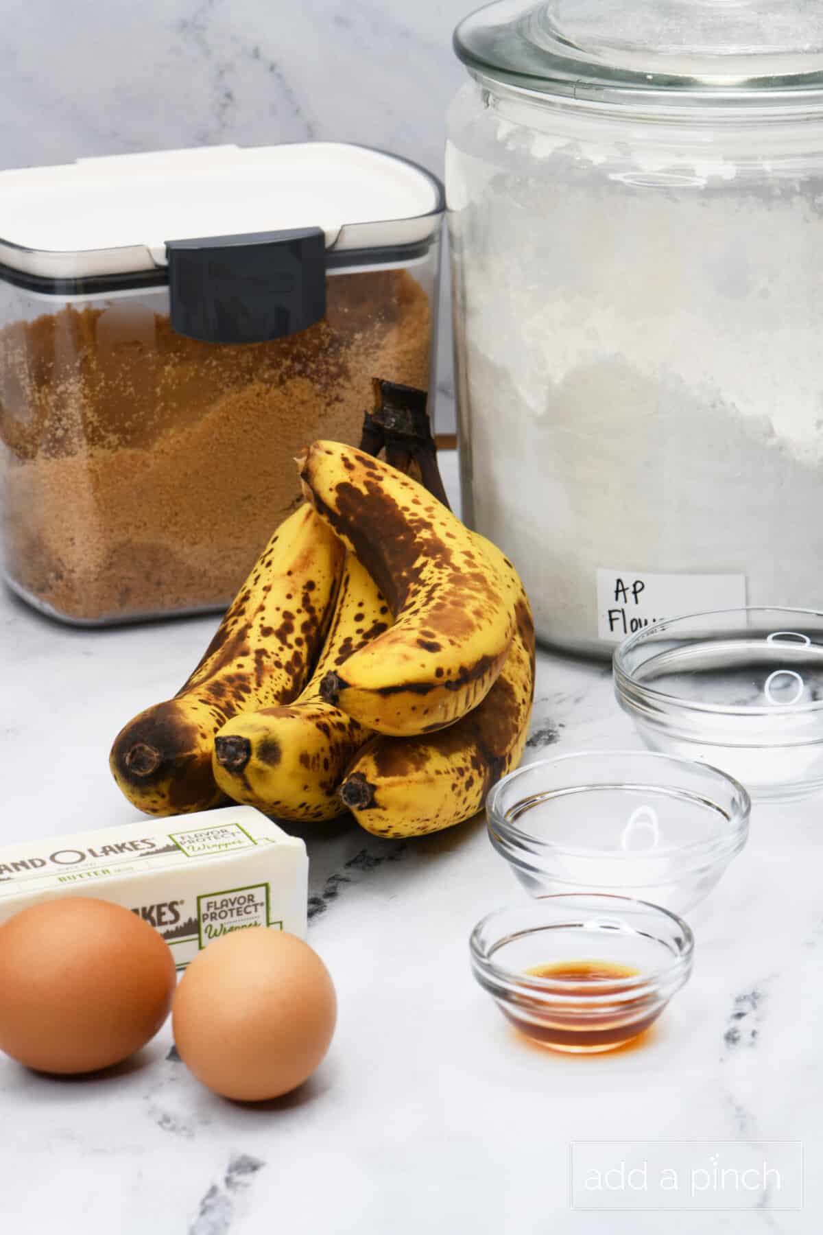 Overripe bananas, eggs, brown sugar, flour and other ingredients for banana bread recipe.