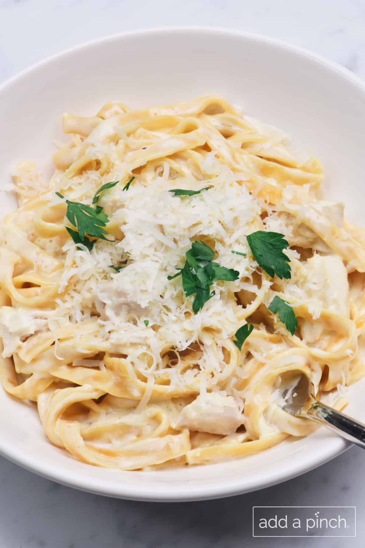 Bowl of chicken Alfredo in a creamy Alfredo sauce with parmesan cheese and parsley.