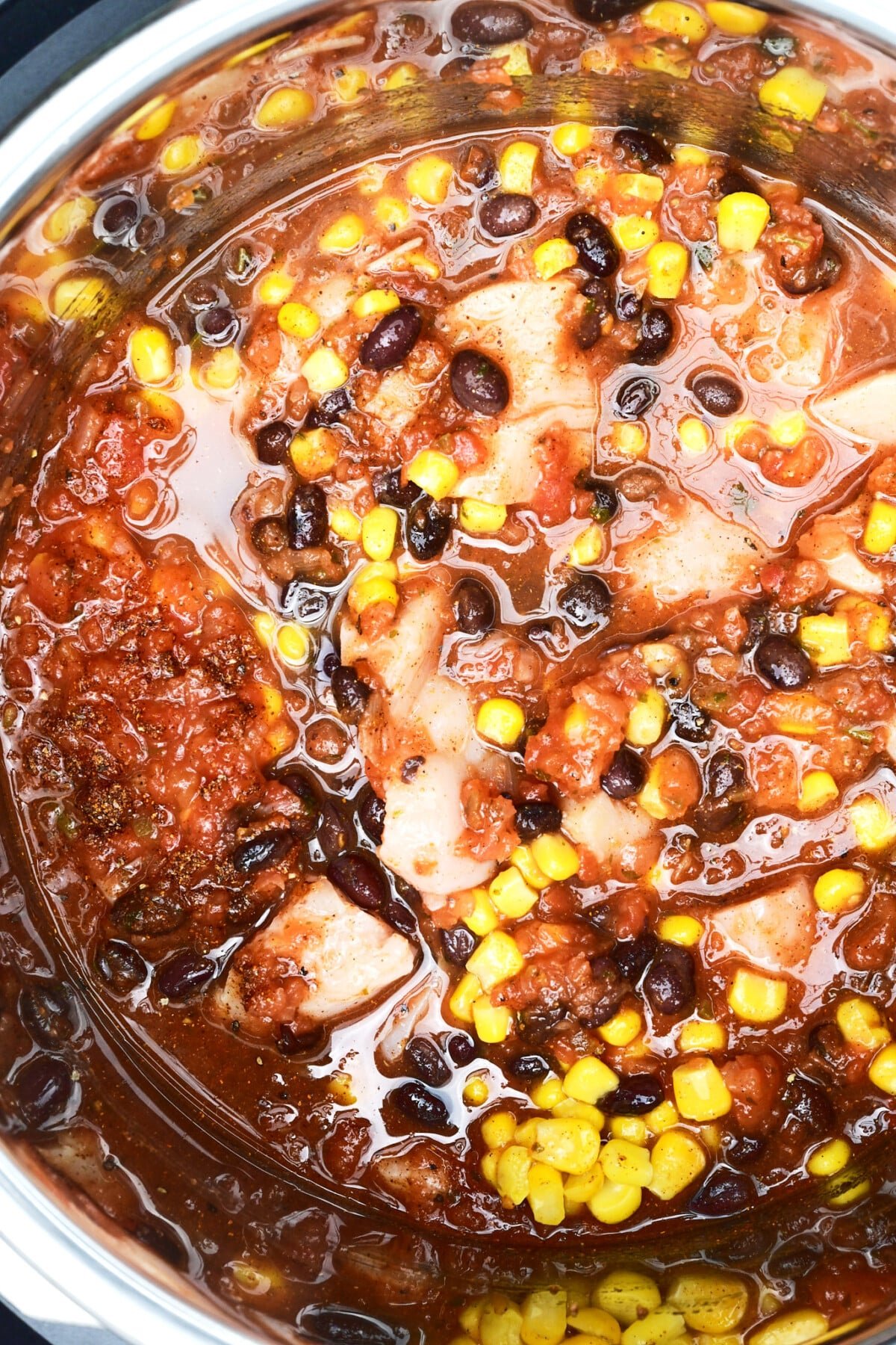 Ingredients for chicken burrito bowls stirred together in Instant Pot before adding rice.