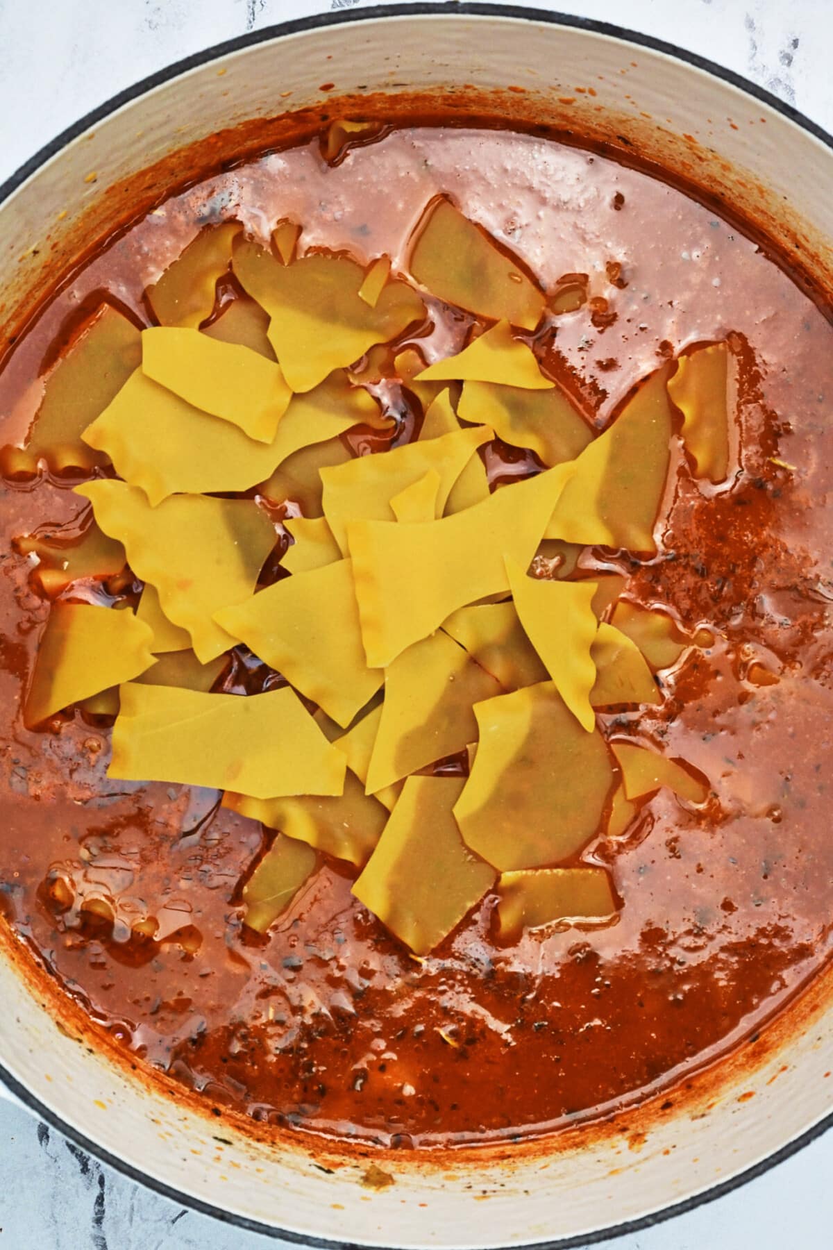 Lasagna soup with broken noodles added in a white Dutch oven.