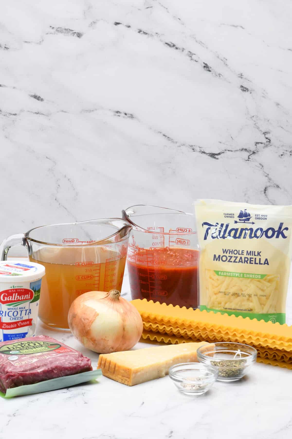 Ingredients to make easy lasagna soup recipe including ground beef, cheeses, marinara sauce, and noodles.