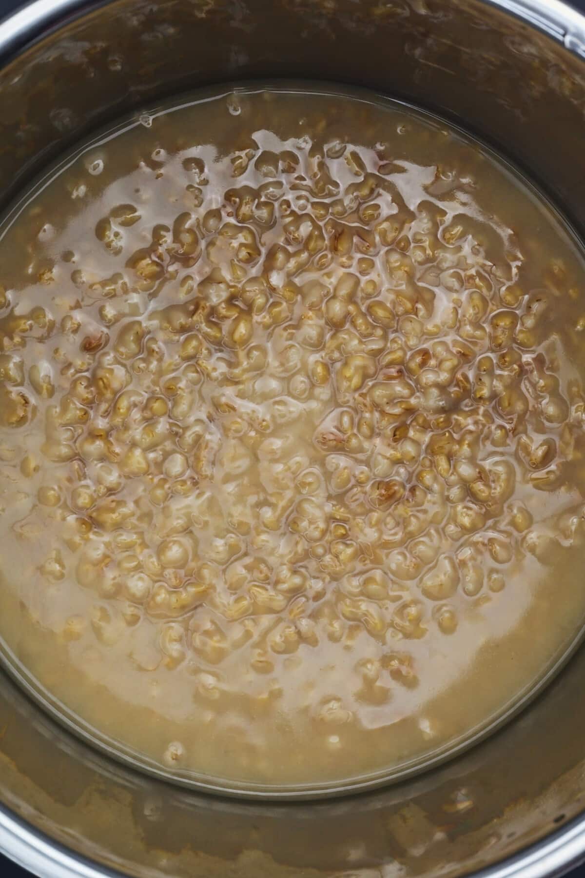 Cooked oat groats recipe in a pot ready to be stirred for serving.