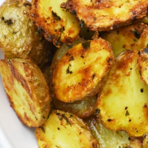 Cripsy parmesan potatoes in a white serving bowl.