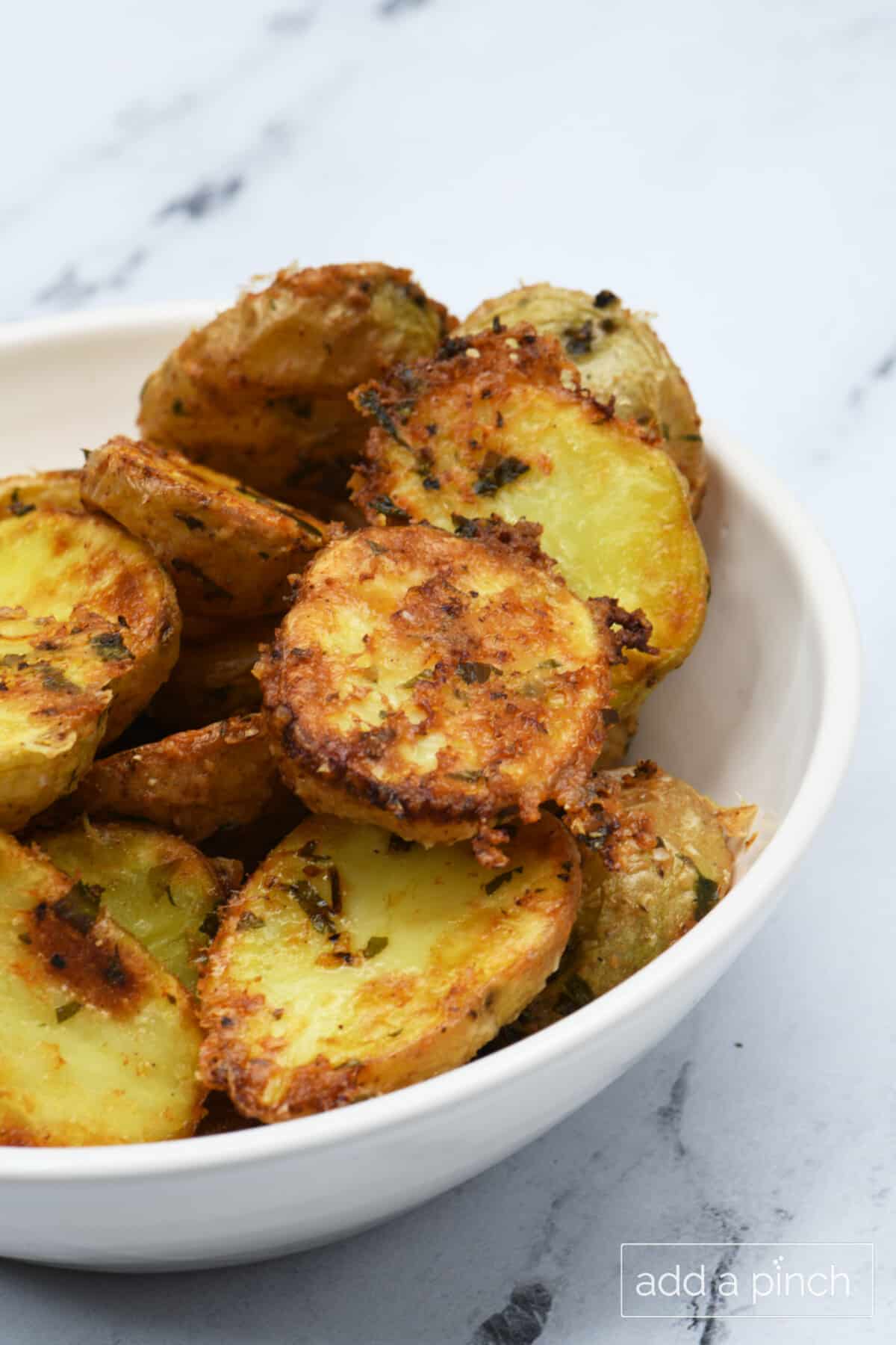 Crispy Parmesan Potatoes baked in the oven! This easy, cheesy side dish recipe with garlic and herbs is perfect for weeknight dinners or holidays. Ready in 30 minutes!