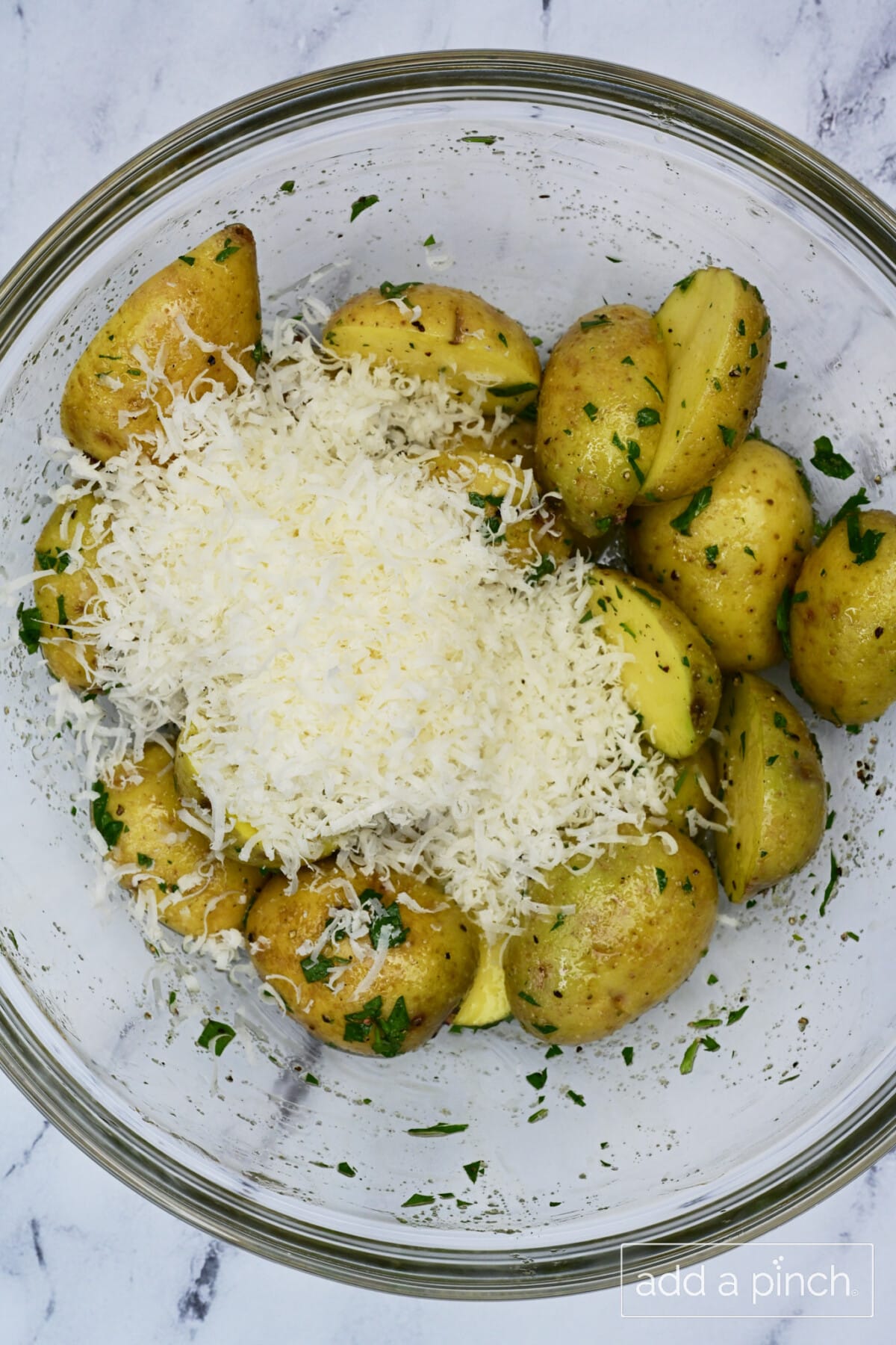 Parmesan cheese on top of sliced baby potatoes ready to be tossed and baked.