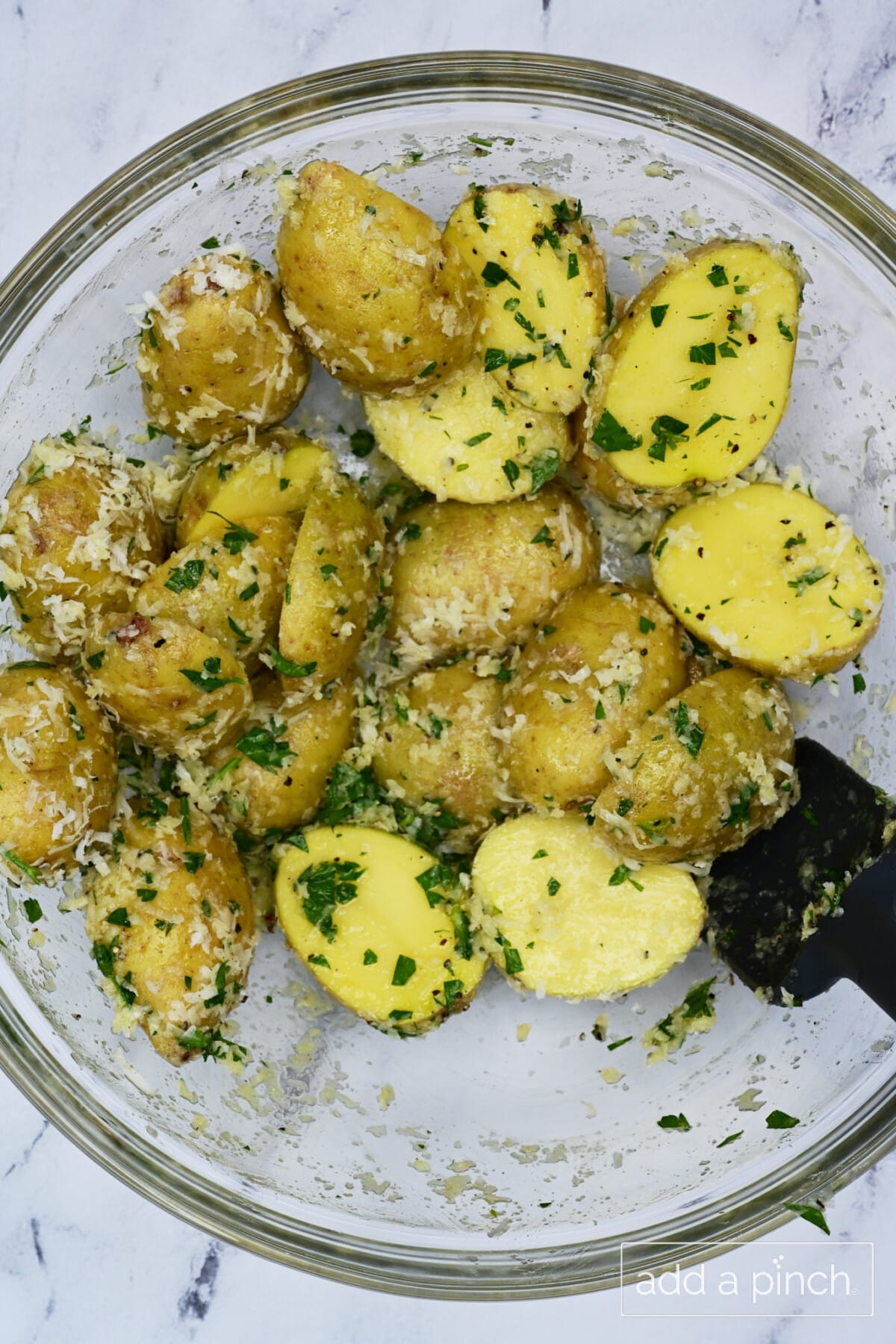 Parmesan coated baby potatoes in a mixing bowl.