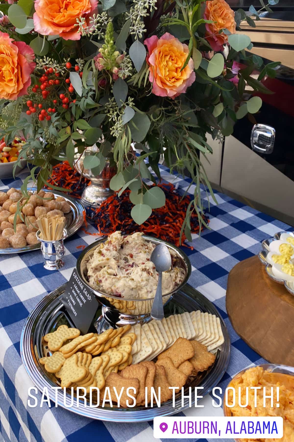 Photograph of tailgate setup with various foods, flowers, and decorations.