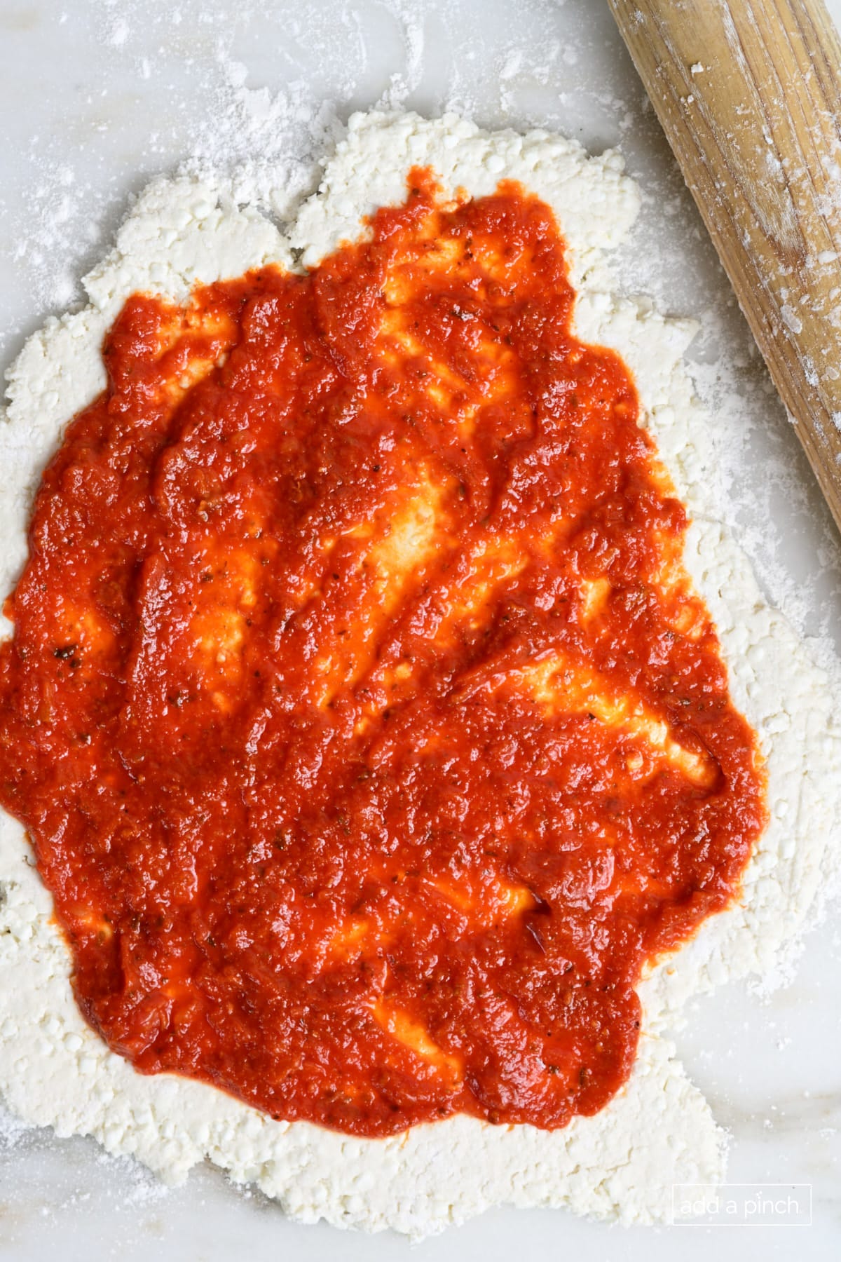 Spread pizza sauce on the pizza dough.