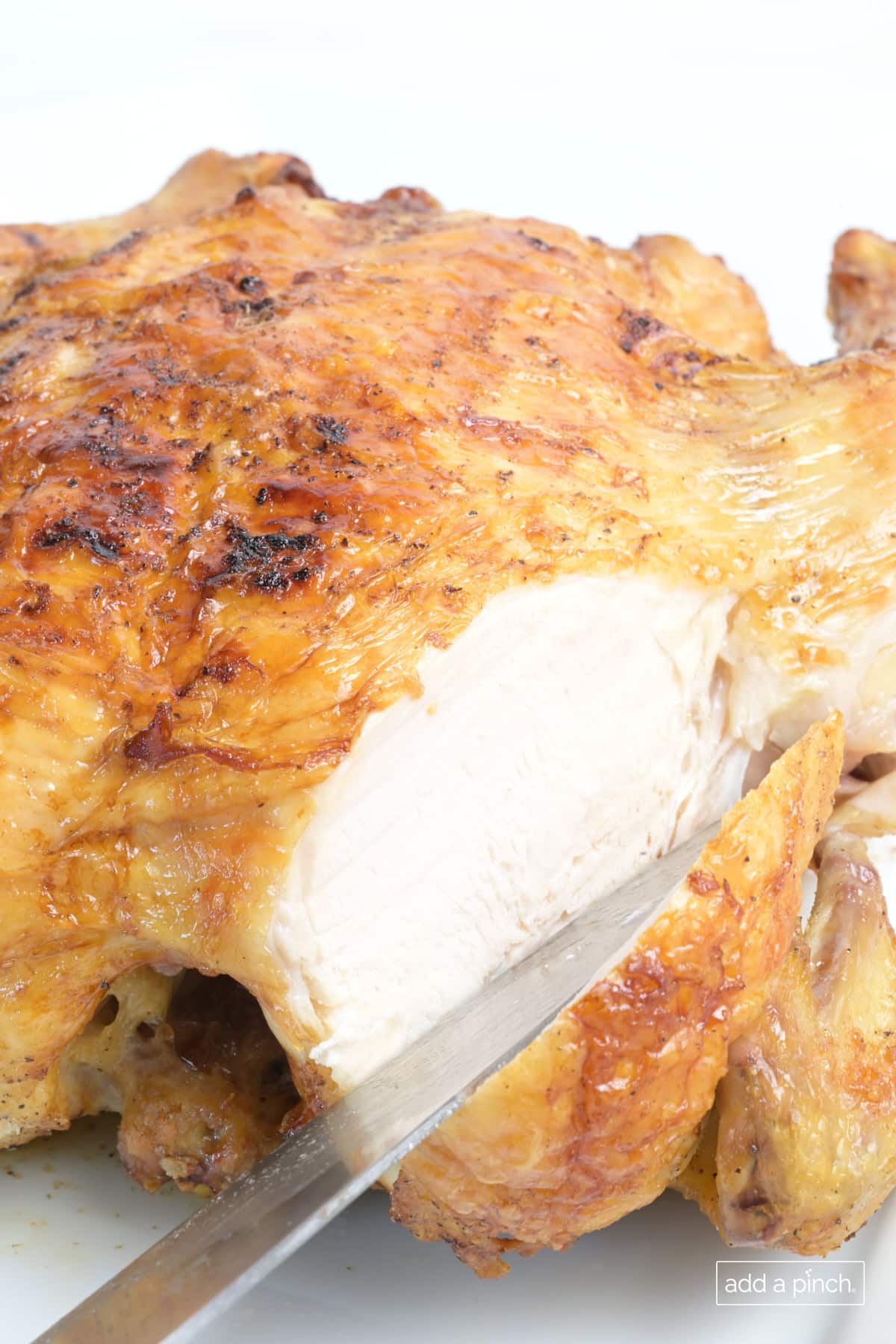 Slice air fryer whole chicken on a white platter.