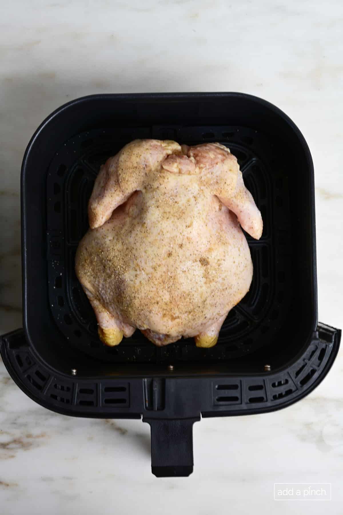 Chicken breast side down in air fryer basket.