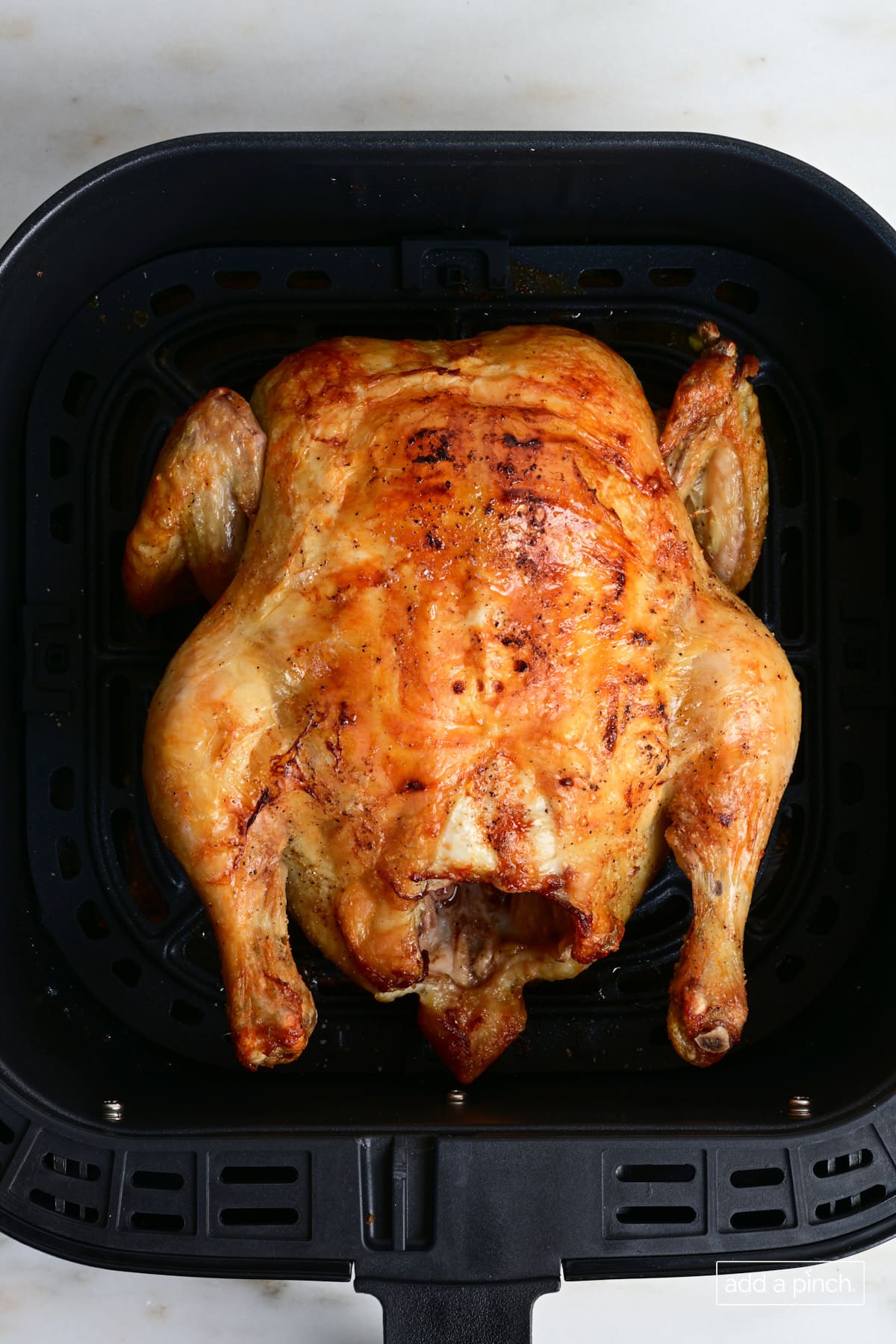 Air Fryer whole chicken in an air fryer basket.