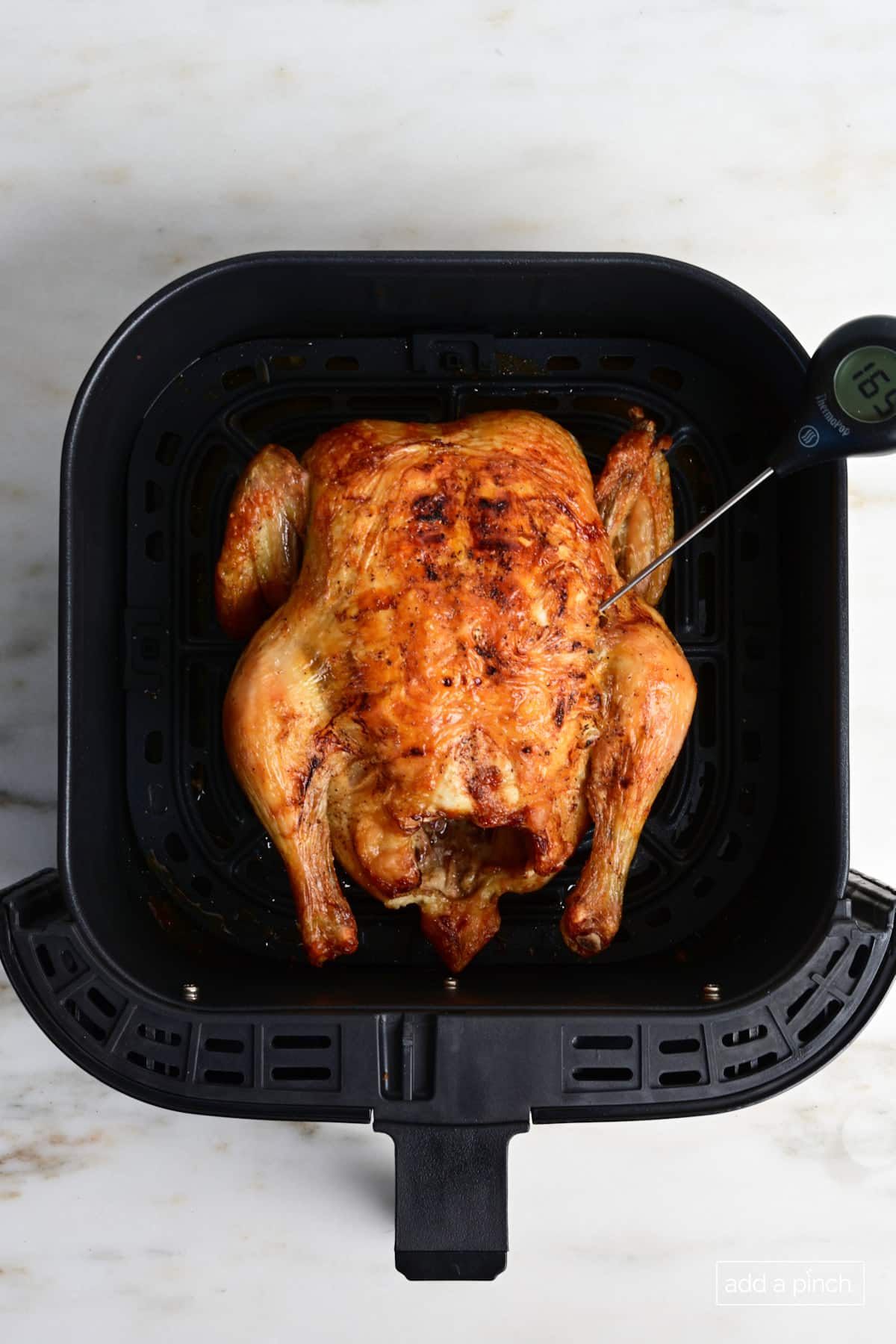 Air Fryer Whole Chicken in air fryer basket with temperature probe.