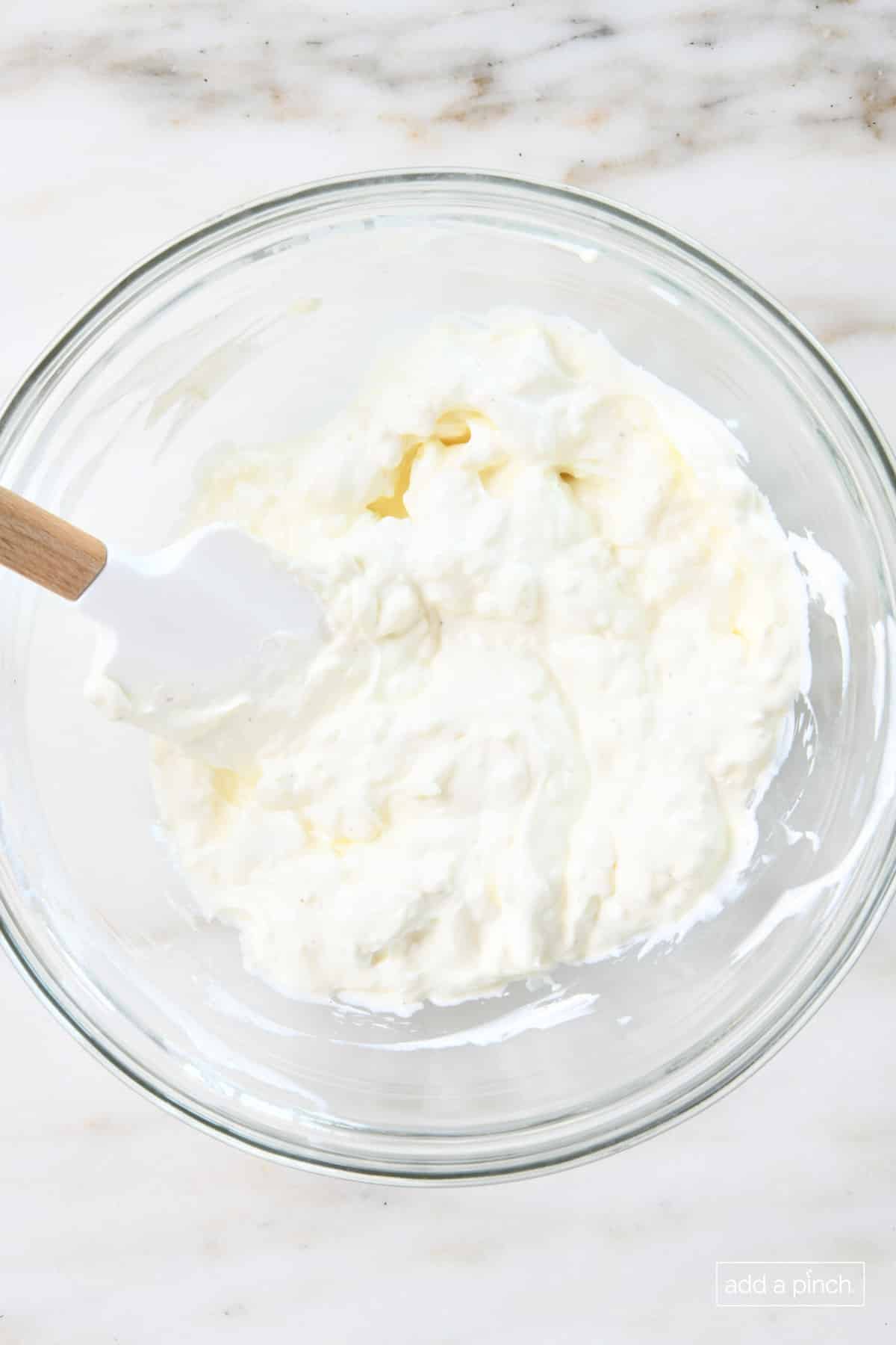 Creamy base of bacon cheddar dip in a glass mixing bowl.
