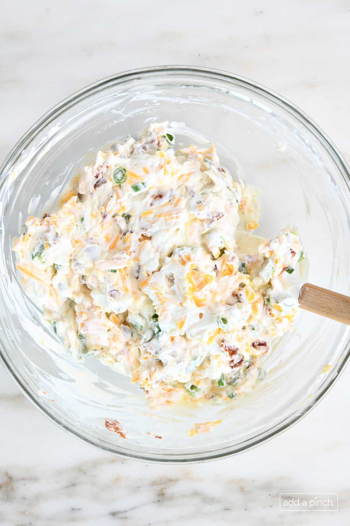 Bacon cheddar dip in a mixing bowl with a spoon.