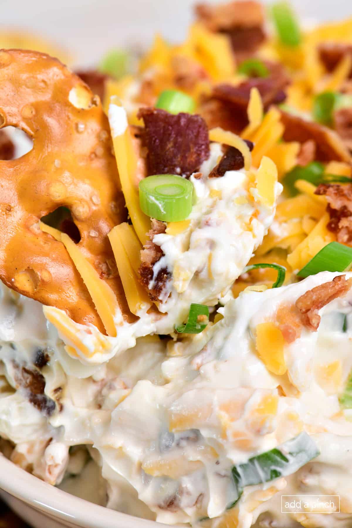 Pretzel chip dipped into bacon cheddar dip.
