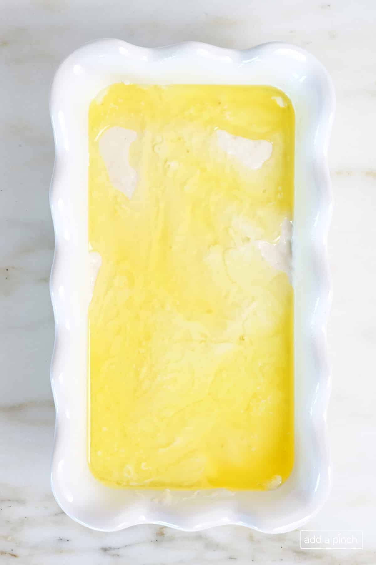 Butter poured over the top of the beer bread batter in loaf pan.