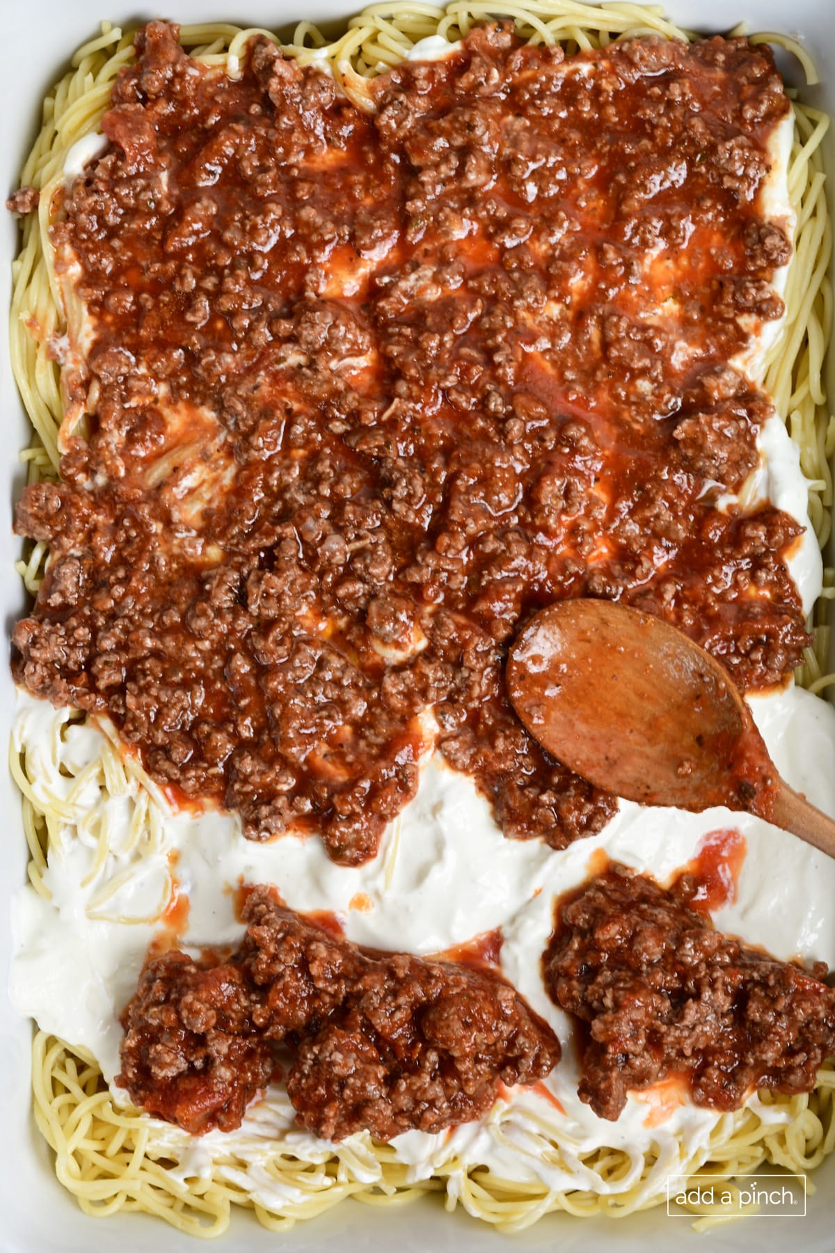 Layering million dollar spaghetti casserole in a baking dish.