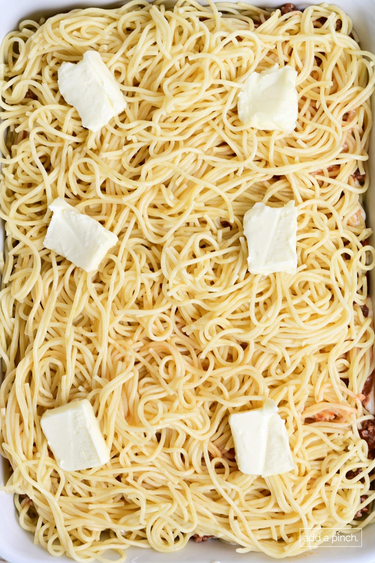 Spaghetti and butter layers in baked spaghetti casserole.