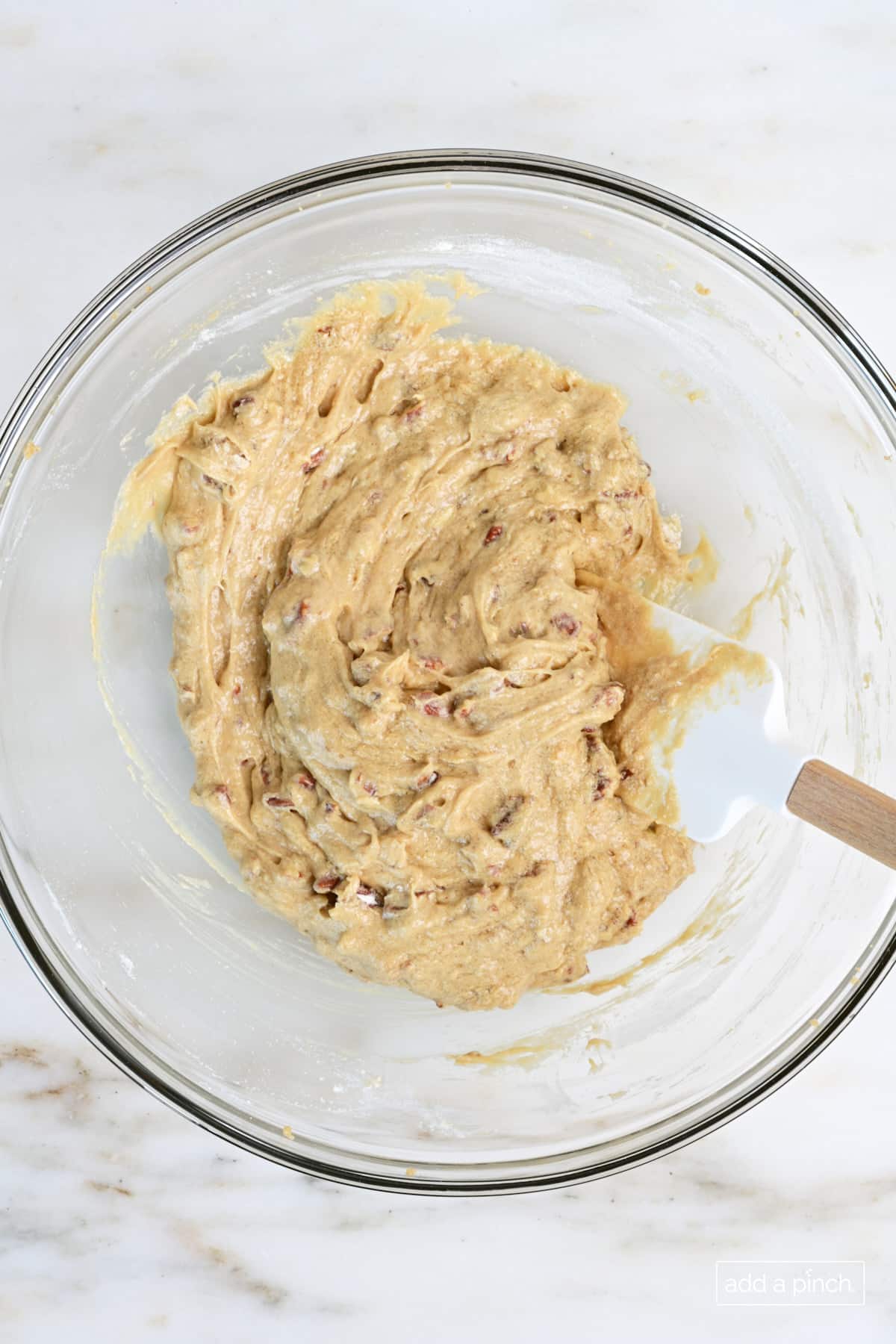 Pecan pie muffin batter in a glass mixing bowl with a spoon.