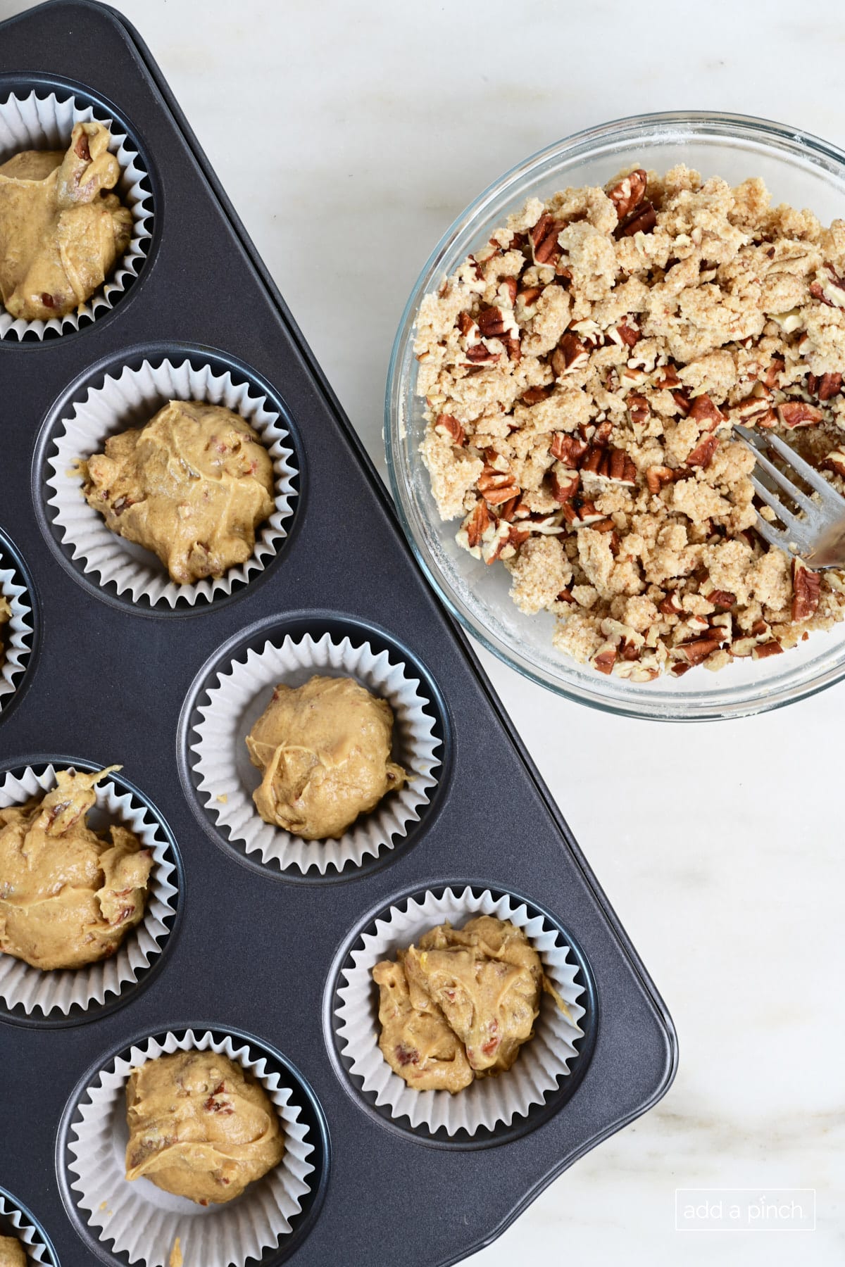 Streusel topping beside muffins in muffin pan.