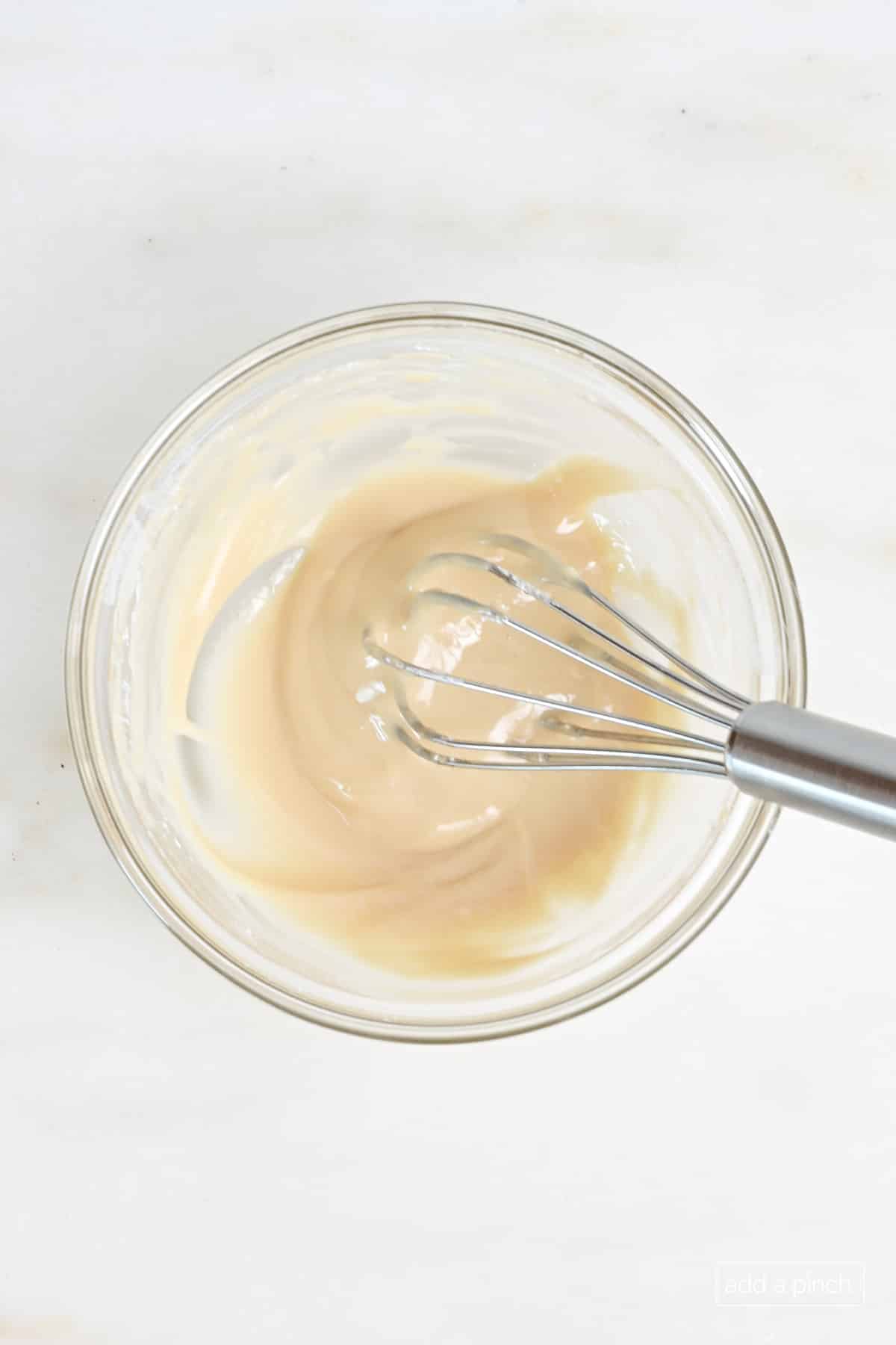 Maple glaze in glass bowl with whisk.