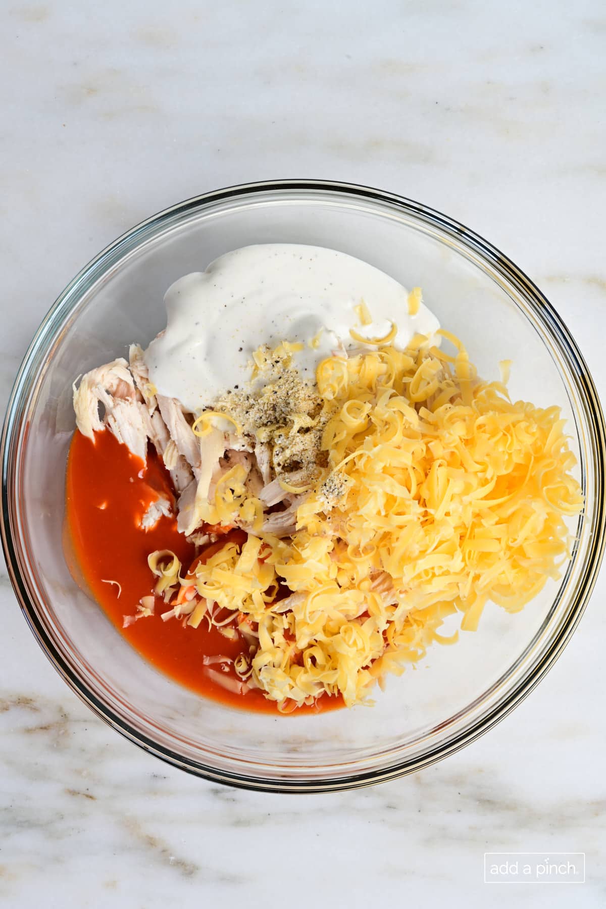 Ingredients for buffalo chicken sliders in a glass bowl.