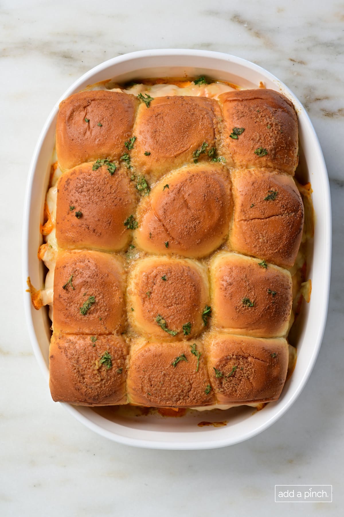 Baked buffalo chicken sliders in a white baking dish.