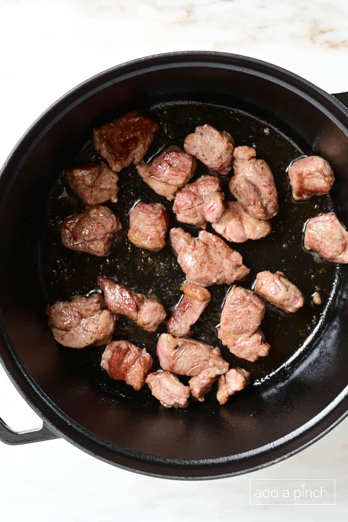 Browned lamb in a Dutch oven.