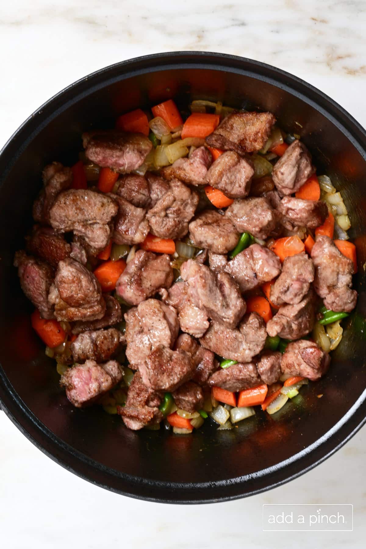 Browned lamb and vegetables in Dutch oven for hearty Irish Stew.