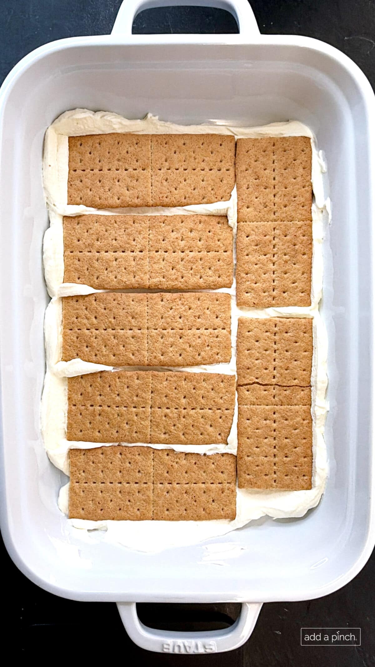 Making the strawberry icebox cake with whipped cream and graham crackers layers.