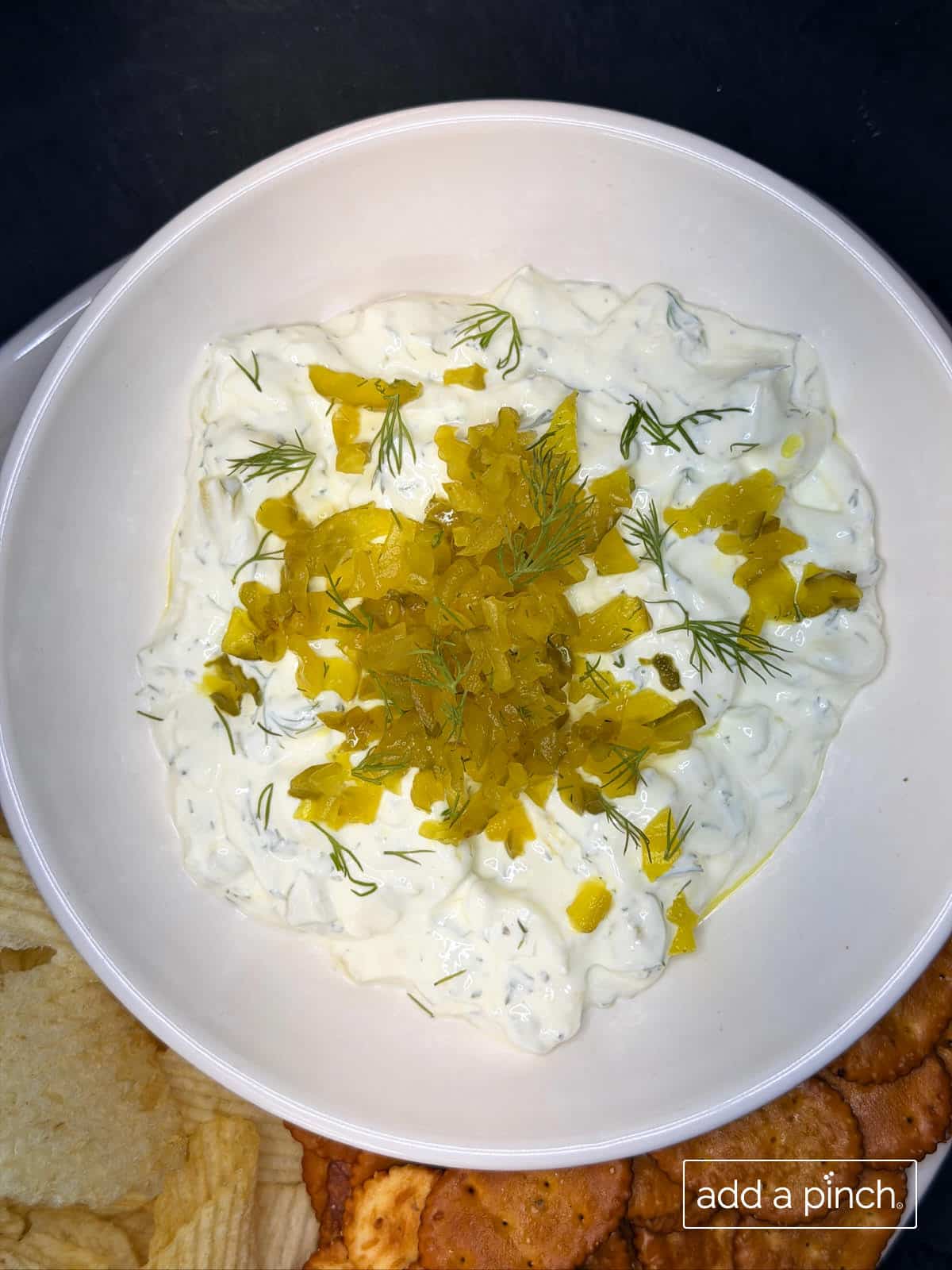 Thick, creamy finished dill pickle dip in a serving bowl garnished with fresh dill and extra pickle slices