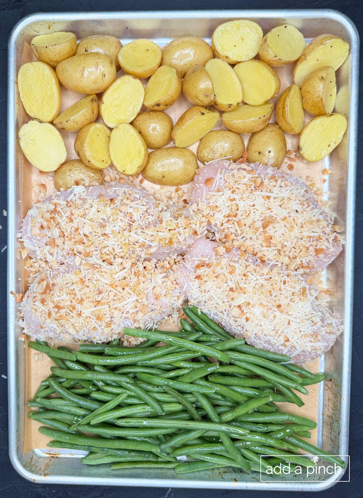 Chicken, baby potatoes and green beans on a sheet pan ready to cook.