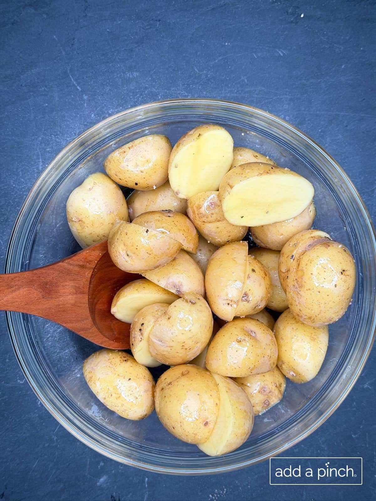 Baby potatoes in a mixing bowl tossed with olive oil and Stone House Seasoning.