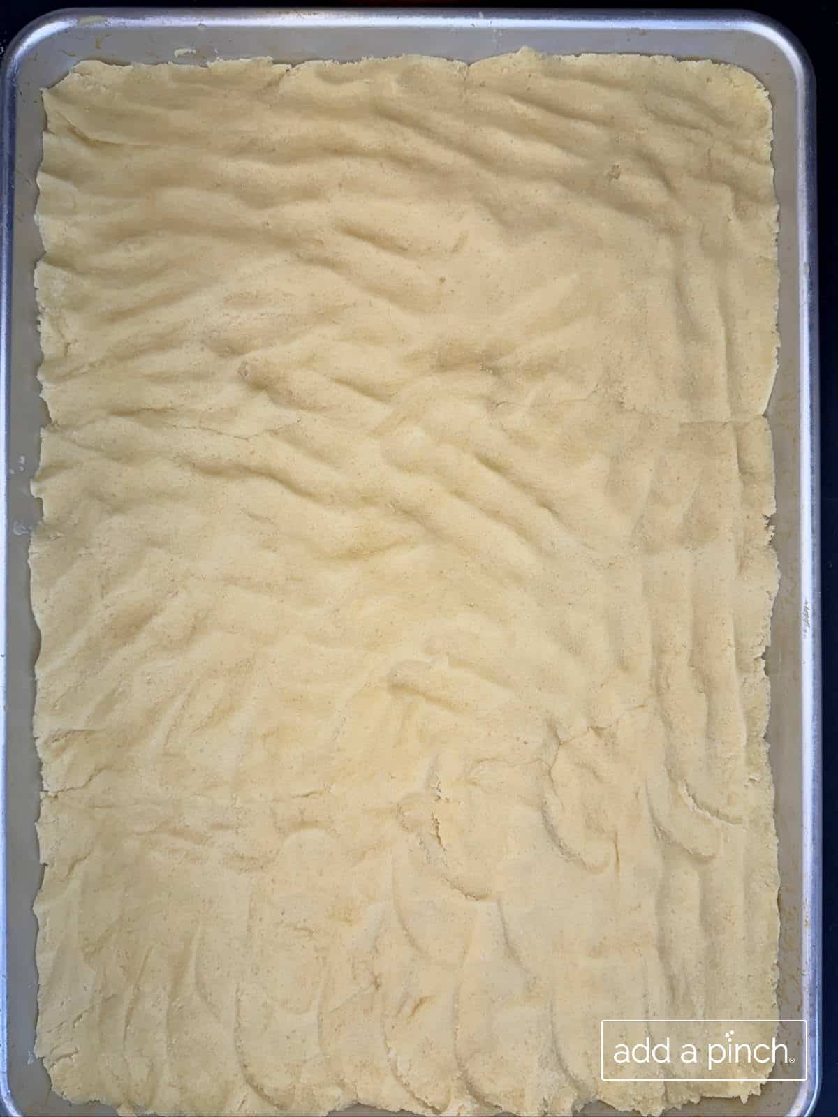 Sugar cookie dough pressed into a rimmed baking sheet for a sugar cookie flag cake.