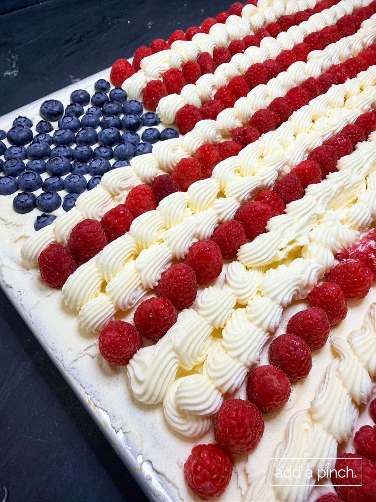 Sugar cookie flag cake with vanilla buttercream frosting, blueberries, and raspberries.