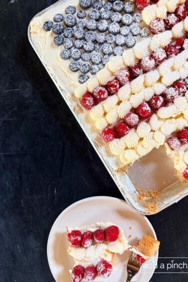Sugar Cookie Flag Cake in a half sheet pan topped with cream cheese or buttercream frosting and fresh blueberries and raspberries arranged as an American flag