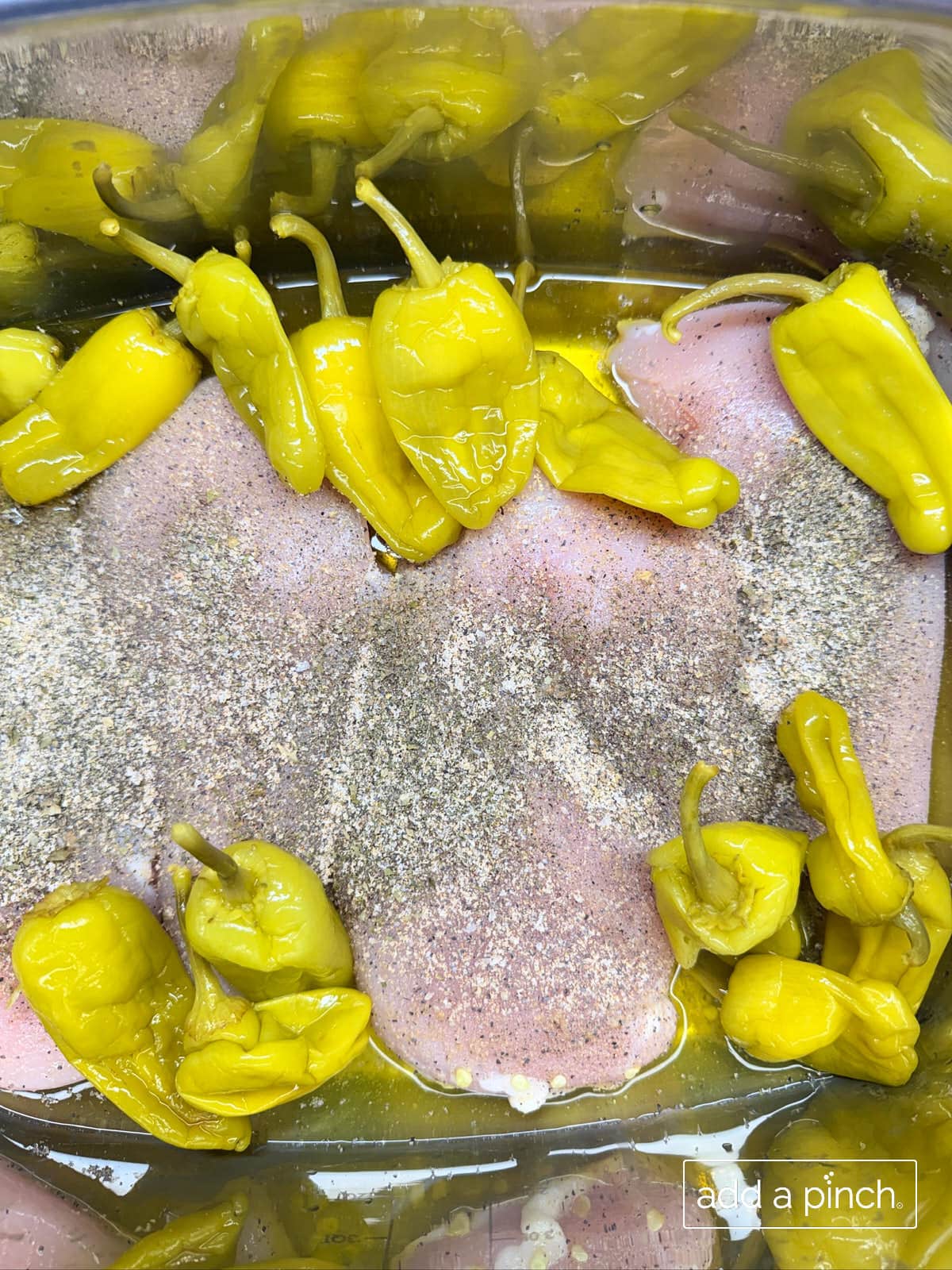 Seasoned chicken with pepperoncini peppers and juices on top.