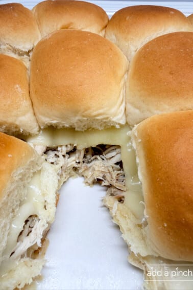 Mississippi chicken sliders with shredded pepperoncini chicken and melted provolone cheese in baking dish.